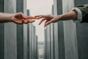 Dos manos extendiéndose para tocarse en un entorno urbano, simbolizando apoyo y orientación en tiempos de incertidumbre.